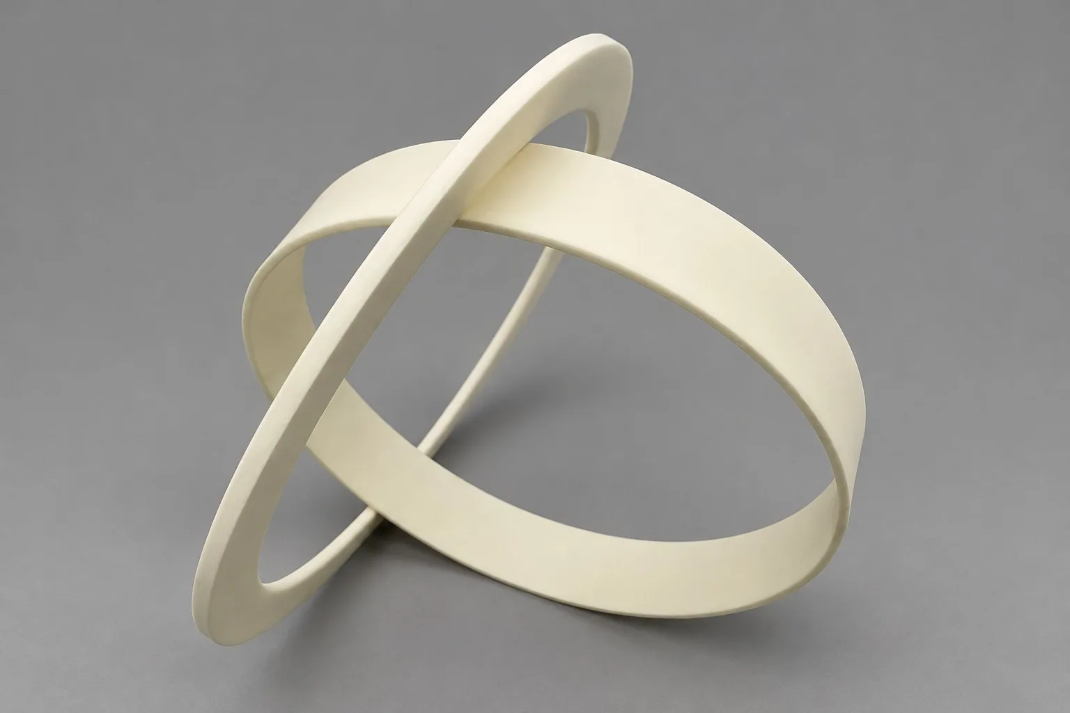 A thin white alumina band formed into an open ring, photographed on a grey studio ground.