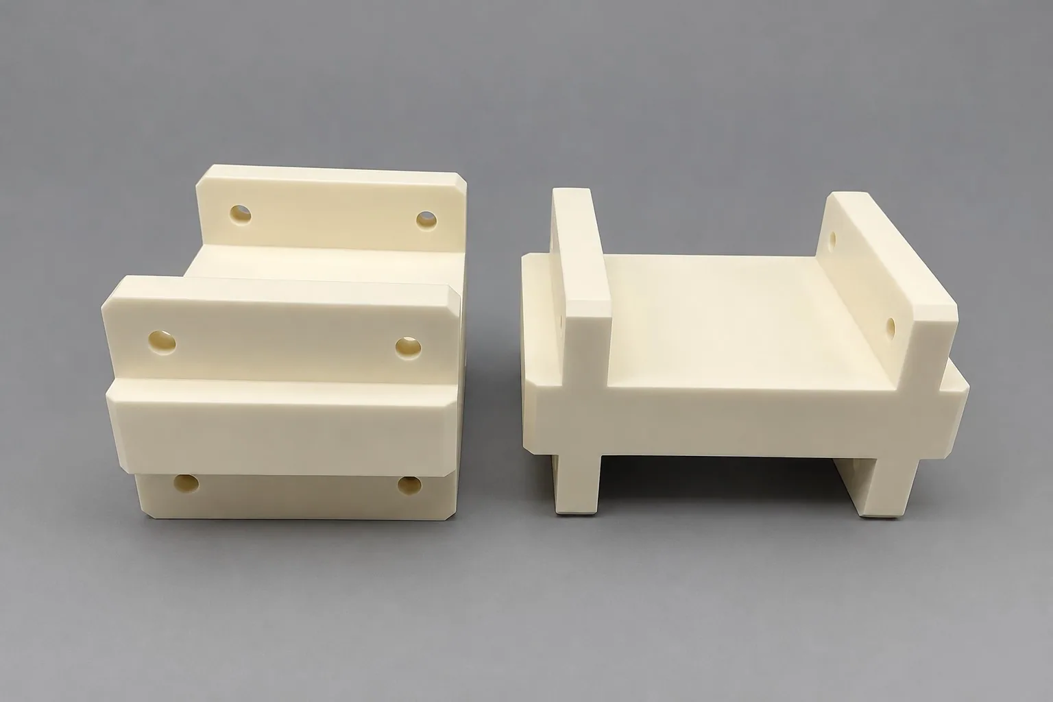 Two white alumina stepped blocks with drilled mounting holes, photographed on a grey studio ground.
