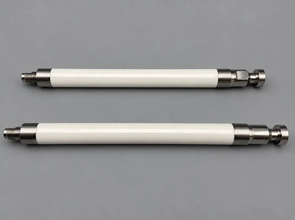 Two long white ceramic shafts on a grey studio ground, each fitted with a threaded metal end at one side and a machined metal fitting at the other.