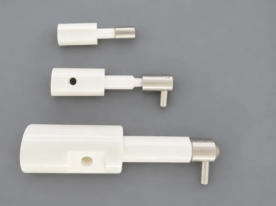 Three plunger assemblies on a grey studio ground, each pairing a white ceramic body with a metal shaft and a short angled side pin.