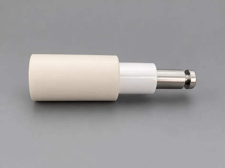 A white stepped cylinder on a grey studio ground with a metal tip fitted to its narrow end and a thin flange behind it.