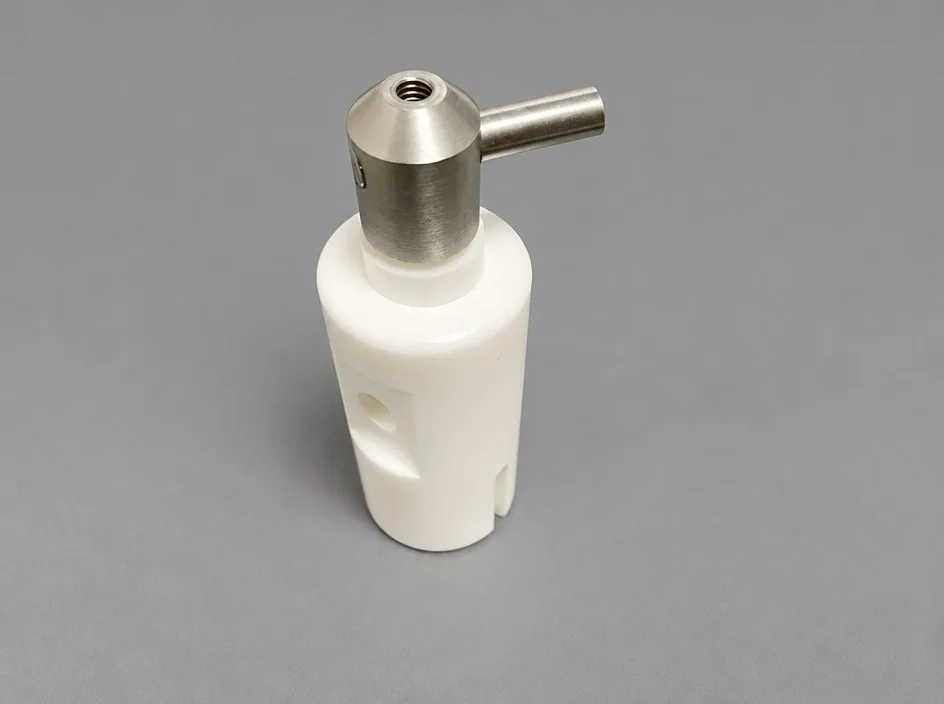 A white body on a grey studio ground with an angled metal head fitted to the top and a side pin projecting from it.
