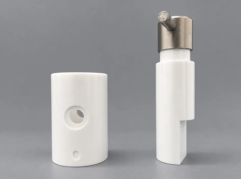 Two white cylindrical bodies on a grey studio ground, one with a large side bore and a smaller bore below it.