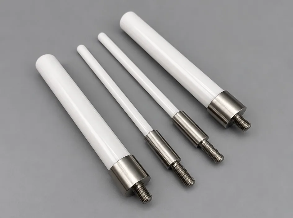 Four white ceramic shafts of different diameters lying in parallel on a grey studio ground, each with a threaded metal end.