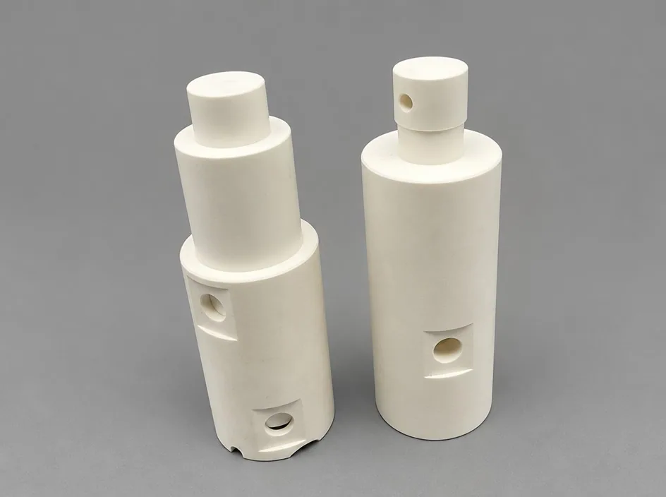 Two white stepped bodies on a grey studio ground, each with a bore through the side wall and a smaller bore near the base.