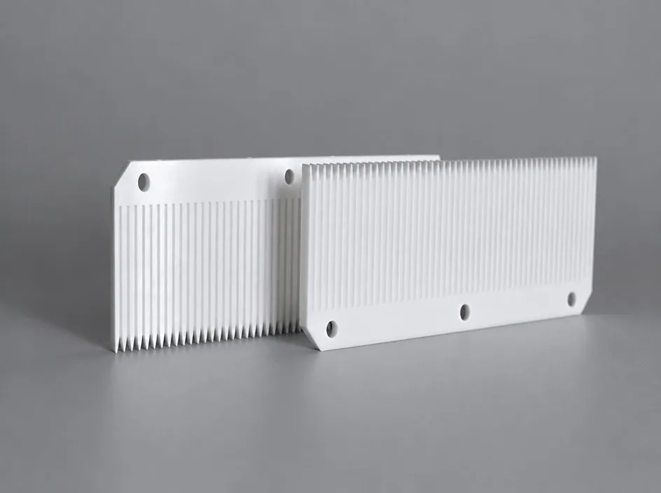 Two white ribbed plates on a grey studio ground, each cut with a dense row of fine vertical ribs and drilled with two bores through the solid end margin.