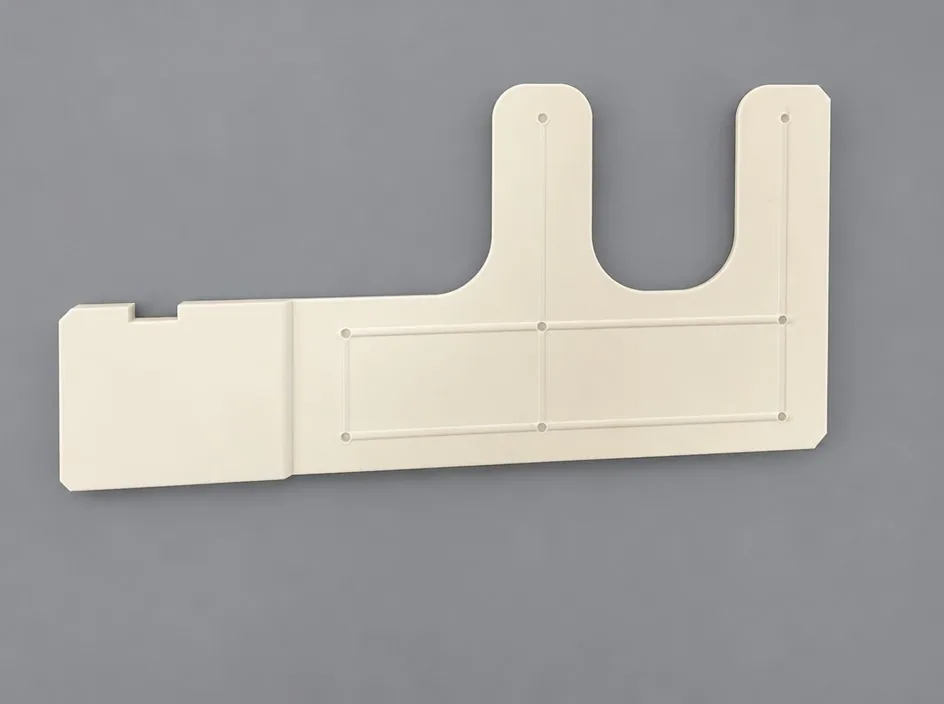 A large white plate on a grey studio ground with a U-shaped slot cut into its upper edge and a shallow raised frame across the body.