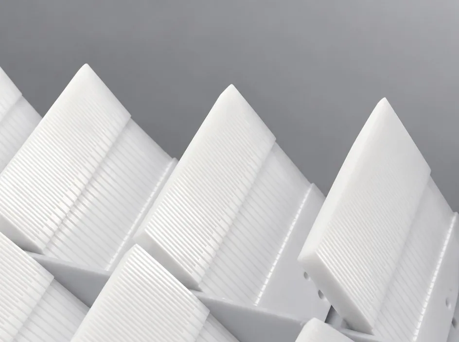 A close view of several white ribbed plates on a grey studio ground, showing the fine parallel rib pattern across the face.