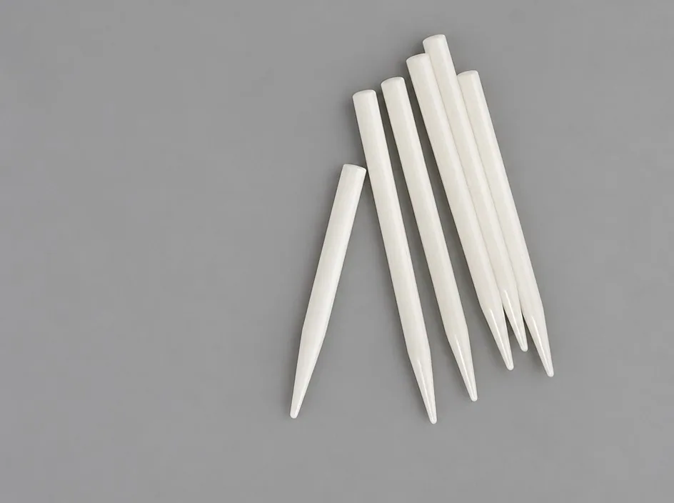 Six white tapered pins fanned out on a grey studio ground, each ground to a point at one end.