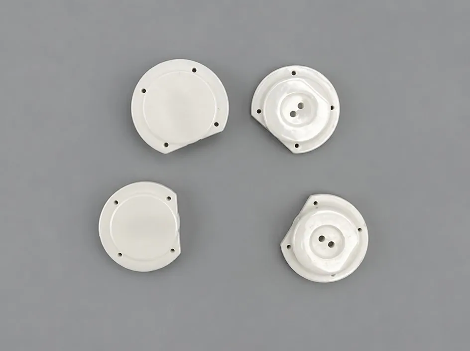 Four white round plates on a grey studio ground, each with a flat chord cut from one edge and three small fixing bores.