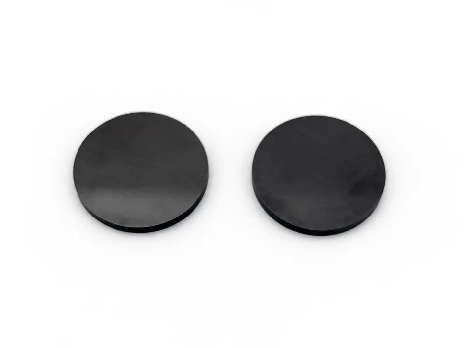 Two thin silicon nitride discs lying flat on a white ground.