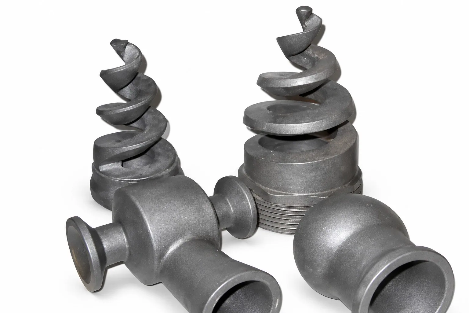 Two black silicon carbide spiral nozzle inserts on a white ground beside two flanged nozzle bodies.