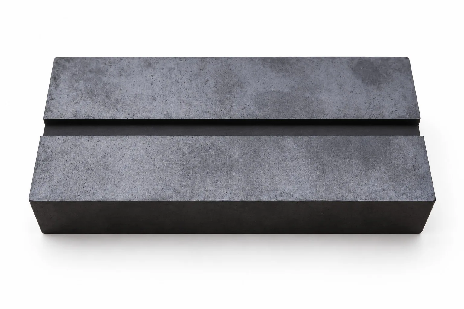 Two thick rectangular black silicon carbide slabs on a white ground, photographed at an angle with their broad faces upward.