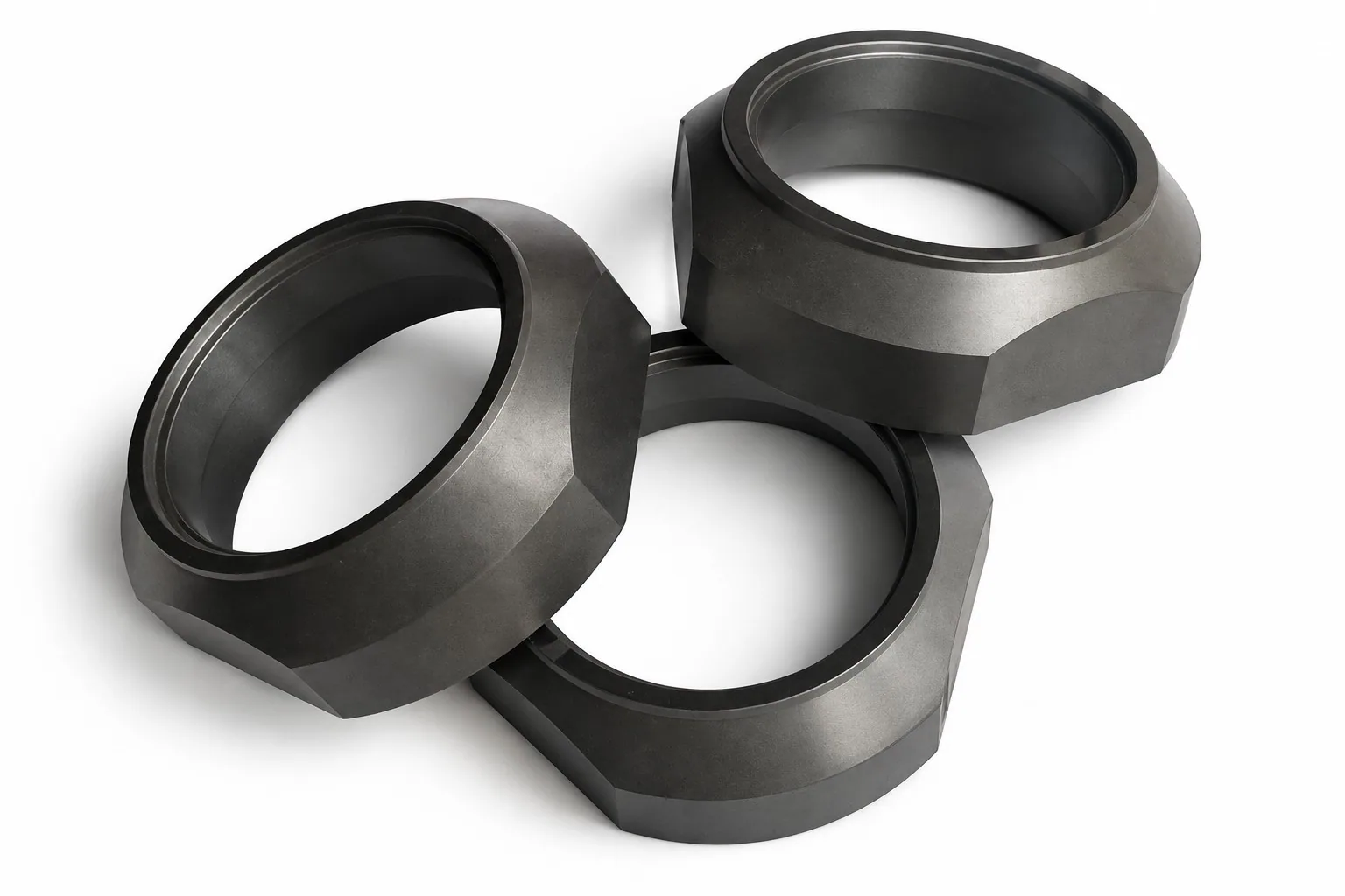 Three black silicon carbide rings with a hexagonal outside profile on a white ground, each carrying an internal sealing groove.