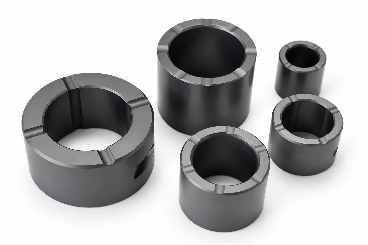 Five black silicon carbide sleeves of different sizes on a white ground, each with notches cut into the top face.
