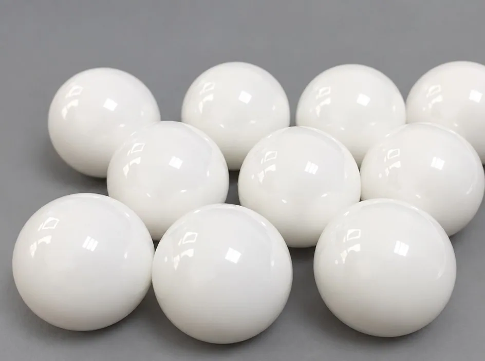 Ten white zirconia balls of similar diameter grouped on a grey studio ground.