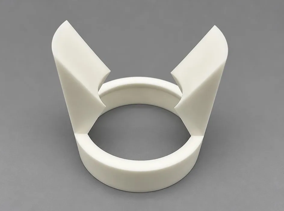 A zirconia ring on a grey studio ground with two curved fins rising from opposite sides of the rim.