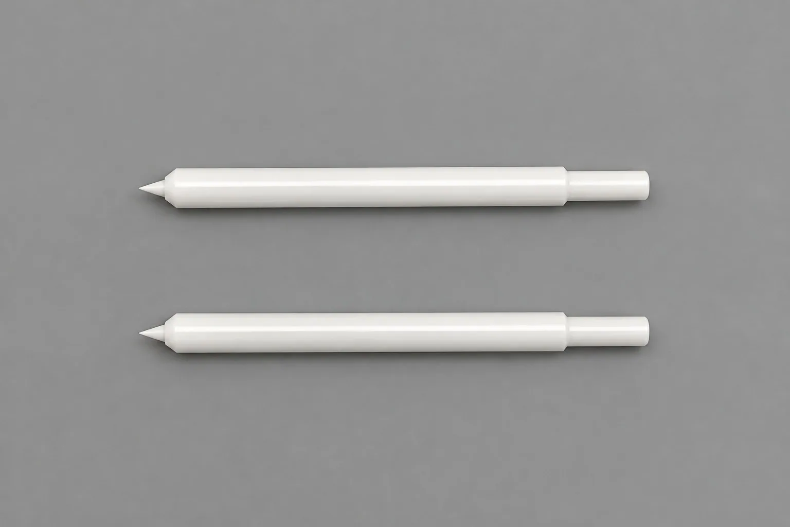 Two zirconia rods on a grey studio ground, each stepped at one end and tapering to a point at the other.